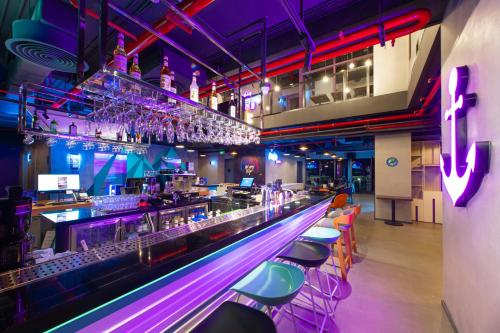 下龙湾SOJO Hotel Ha Long的一间酒吧,配有紫色和粉红色的灯光和酒吧凳子