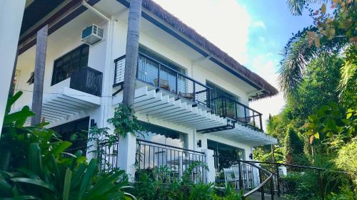 MataasnakahoyVillas by Eco Hotels Batangas的带阳台和楼梯的白色建筑