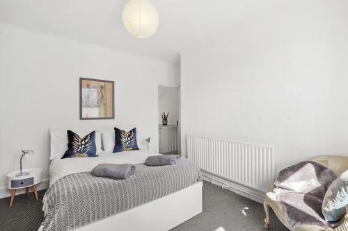 伦敦Stunning Victorian property near Canary Wharf!的白色卧室配有床和椅子