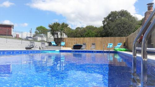 大托灵顿Greenways Valley Holiday Park的一个带椅子和围栏的蓝色游泳池