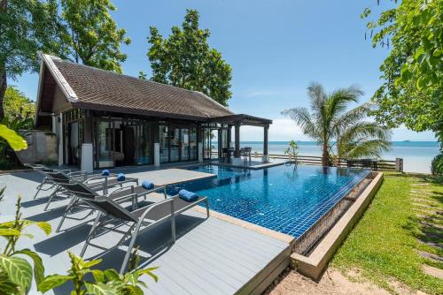 班邦宝Beach Front Villa的一个带椅子的游泳池和一个毗邻大海的凉亭