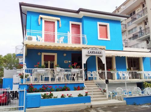 里米尼Hotel Lariana的蓝色的建筑,设有白色的阳台和楼梯