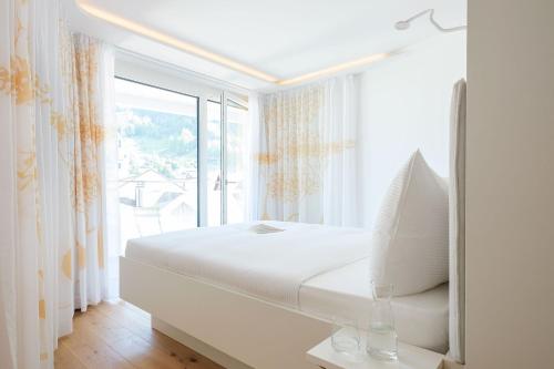 菲茨瑙Neuro Campus Hotel的白色的卧室设有床和大窗户