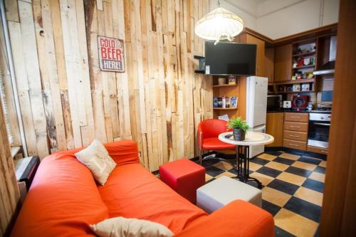 布达佩斯阿卡西亚旅舍的一间带橙色沙发的客厅和一间厨房