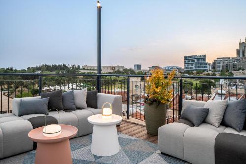 耶路撒冷Albi Boutique Hotel - Traveler's Choice 2024的阳台设有沙发和桌子,享有城市美景。