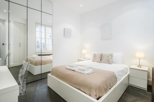 伦敦Beautiful 2 bedroom Covent Garden apartment的白色卧室设有一张大床和镜子