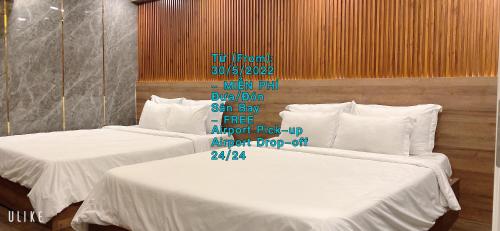 胡志明市Ha Noi Hotel near Tan Son Nhat International Airport的墙上有标牌的房间的两张床