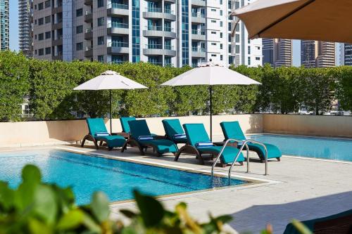 迪拜迪拜码头丽笙酒店的一组椅子和遮阳伞,位于游泳池旁