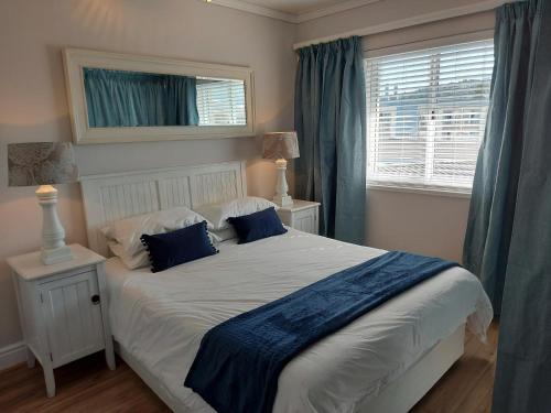 克尼斯纳Belle View @ Knysna Quays的卧室配有带蓝色枕头的大型白色床