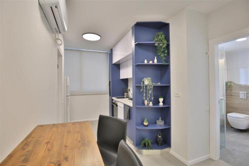 内坦亚Cozy and stylish 1-bedroom apartment的一间设有桌子和蓝色架子的用餐室