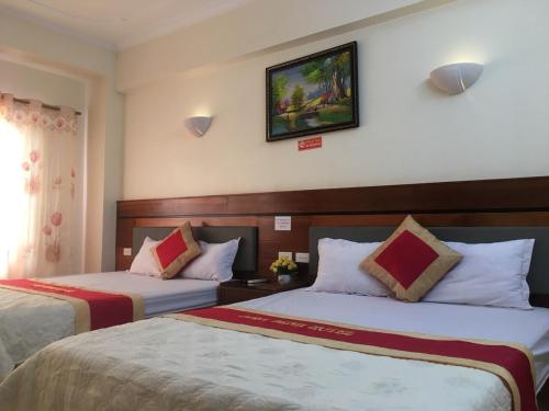 格卢市社Khách sạn NHẬT MINH Cửa Lò的酒店客房设有两张床,墙上挂着一张照片。