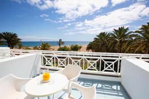 卡门港拉赫里亚时尚酒店的一个带桌椅和海滩的阳台