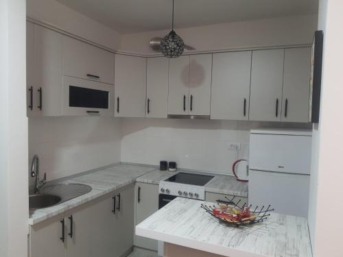 波扎雷瓦茨Apartman M的厨房配有白色橱柜和柜台上的一碗水果