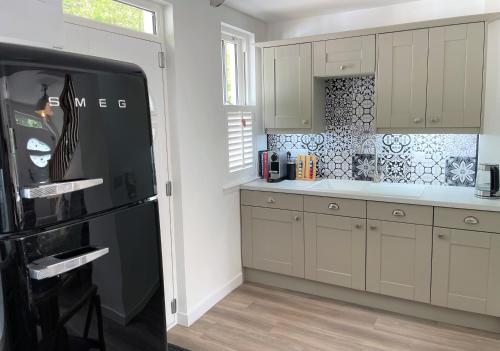 CairnbaanCoorie Doon的厨房配有白色橱柜和黑色冰箱。