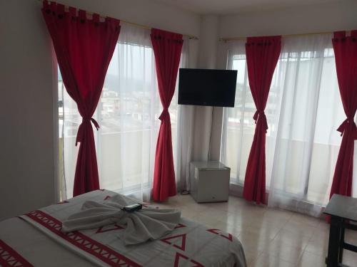 莫科阿Hotel Luis Ángel的一间卧室配有红色窗帘和一张带电视的床