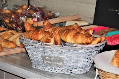 塞纳河畔罗米伊L'Hôtel du Marais Romilly Centre的柜台上一篮羊角面包和其他糕点