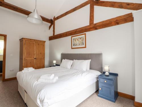 惠特彻奇The Cart House的卧室配有白色大床和蓝色床头柜。