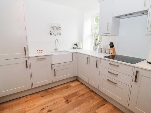莫珀斯Sarah's Cottage的白色的厨房配有白色橱柜和木地板