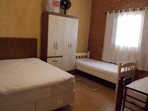 布罗塔斯Cantinho rústico simples & aconchegante的一间卧室设有两张床、一个橱柜和一个窗口。