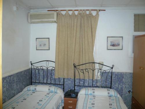 穆尔西亚坎波伊膳食公寓酒店的卧室设有两张单人床,铺有蓝色瓷砖