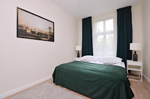 索波特Helska By the Sea的一间卧室配有一张带绿色床单的床和一扇窗户。