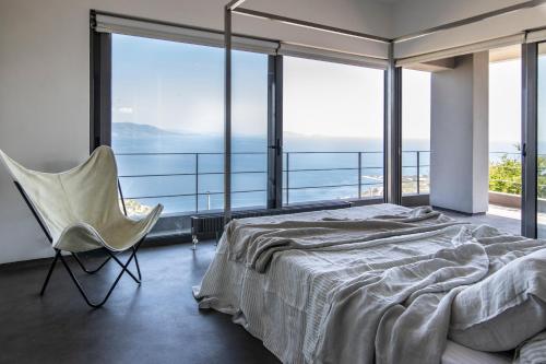 斯尼斯Seaview Villa Schinias的卧室配有床、椅子和大窗户