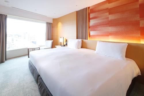 东京东京雅叙园酒店的一张大白色的床,位于一个设有大窗户的房间