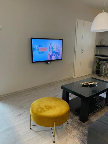斯科普里Cosy Apartment on an amazing location!的客厅配有桌子、黄色凳子和电视