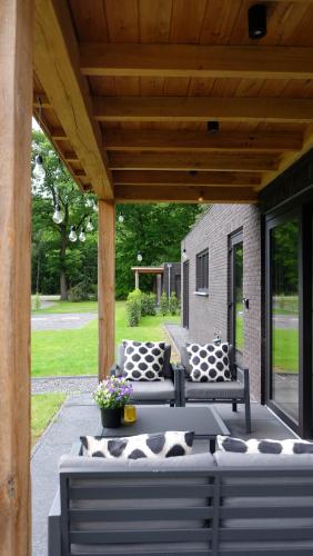 福尔特赫伊曾The Black Oak - Luxe bungalow met prive sauna的天井配有两张沙发和一张带枕头的桌子。