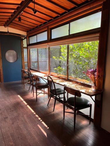 北九州Mojiko Guesthouse PORTO的一张大窗房内的长桌子和椅子