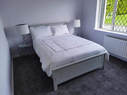利默里克4 Bedroom, 15 min to Limerick city Quiet Retreat.的卧室配有白色床、两盏灯和一扇窗户。