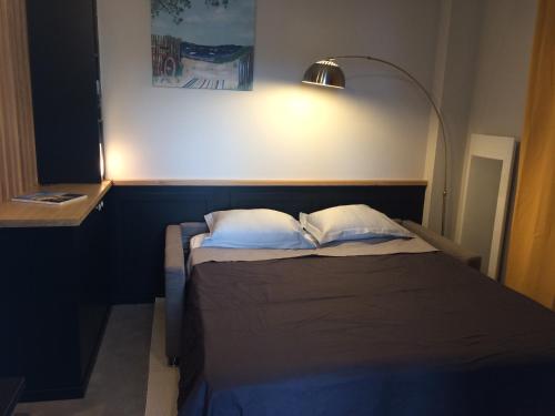 迪纳尔Dinard: studio à 100 m de la plage de L'Ecluse的一张带两个枕头的床和台灯