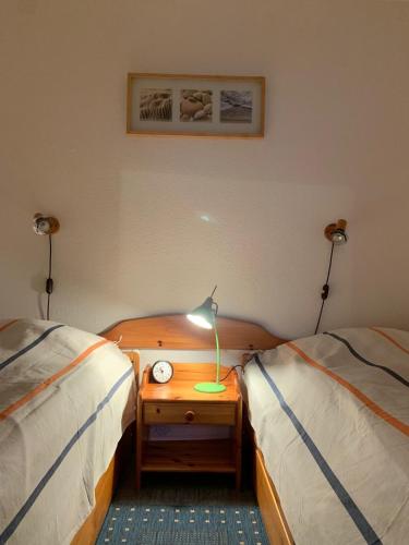 达默FeWo Seeschloss Nr 5的一间卧室配有两张床和一张带台灯的桌子