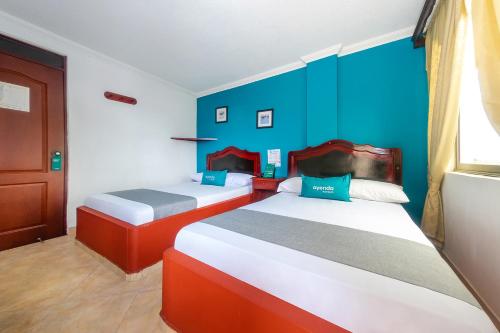 波帕扬Ayenda La Terraza Popayán的蓝色墙壁客房的两张床