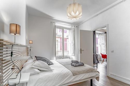 普奇塞达3.2 Apartamento Coma Oriola的白色卧室配有一张大床和吊灯