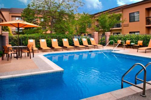 米德尔敦纽波特米德尔顿万怡酒店的一个带椅子和桌子的游泳池以及一把遮阳伞