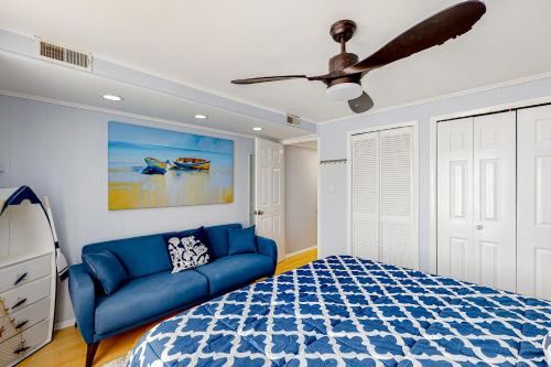 大洋城The Quarterdeck OC的一间卧室配有蓝色的沙发和吊扇