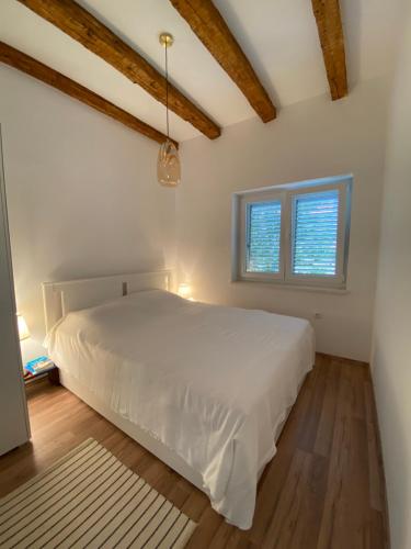 维利伊兹Sweet house of Iž的卧室配有白色的床和2扇窗户。