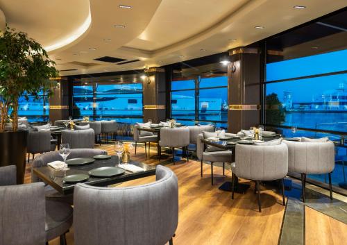 伊斯坦布尔Crowne Plaza - Istanbul Tuzla Viaport Marina, an IHG Hotel的餐厅设有桌椅和大窗户。