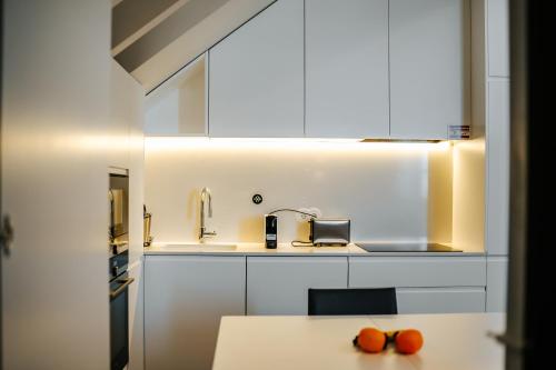 维亚纳堡Casa Guerreiro - Regina Hotel Group的厨房配有白色橱柜和桌子上的橙子