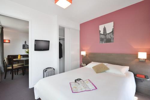 图卢兹图卢兹圣西普里安爱达格公寓式酒店的卧室配有白色的床和粉红色的墙壁
