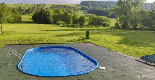 下乌斯奇基Domki - Noclegi Pod Ostrym Działem的蓝色的热水浴缸,位于带田野的庭院