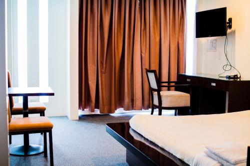 达沃市贝莹套房公寓式酒店的酒店客房,配有一张床、一张桌子和椅子