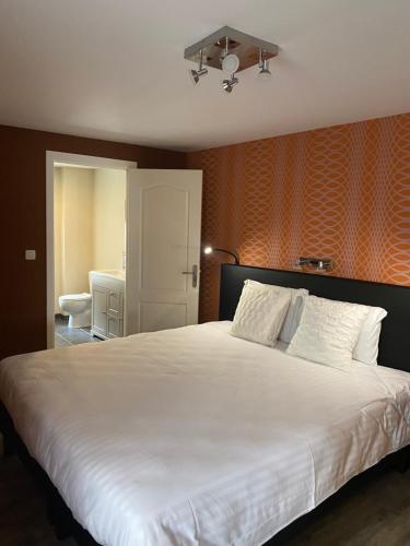 布永LA CACHETTE Maison 3Ch 3SdB Salon Wifi的一间卧室配有一张白色大床和橙色墙壁