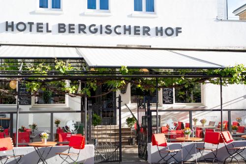 柯尼希斯温特Storyhotel Bergischer Hof Königswinter的大楼前设有桌椅的餐厅