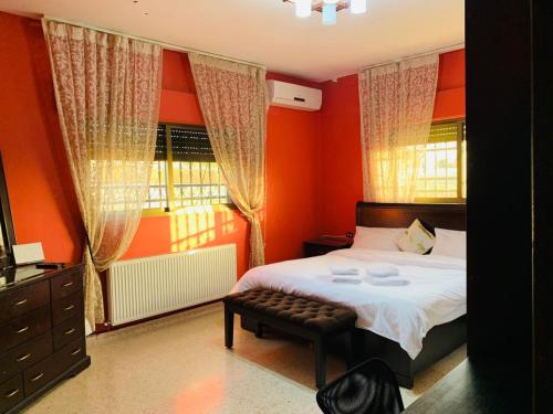 马达巴Laura’s Modern Villa的一间卧室拥有橙色的墙壁、一张床和窗户