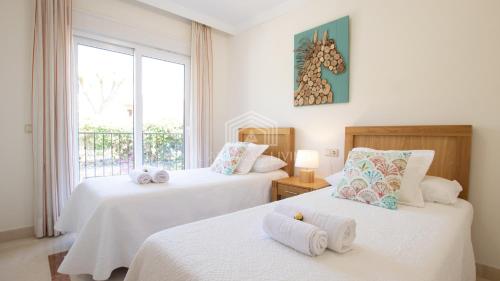 马拉加Spacious perfectly maintained house with private garden and communal pool in Riviera del Sol的一间卧室设有两张带白色床单的床和窗户。
