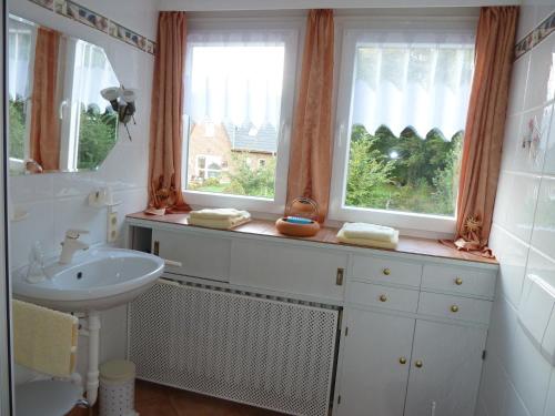 代斯特尔山麓巴德明德尔Gästehaus Villa Kreativ Susanne Lay的一间带水槽的浴室和两个窗户