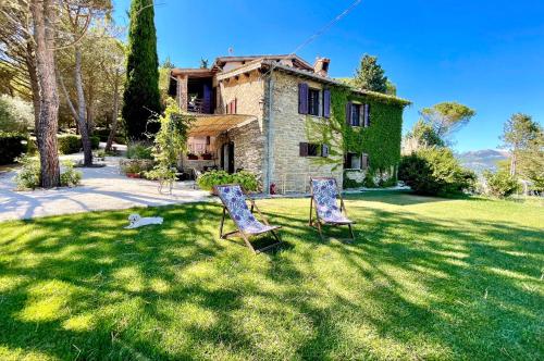古比奥La Panoramica Gubbio - Maison de Charme - Casette e appartamenti self catering per vacanze meravigliose!的房子前面的草上两把椅子