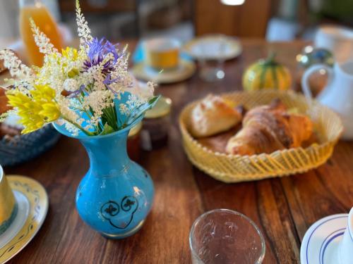 潘蓬La Corne de Cerf, Forêt de Brocéliande的一张桌子,上面有蓝色花瓶,上面有鲜花和一篮面包